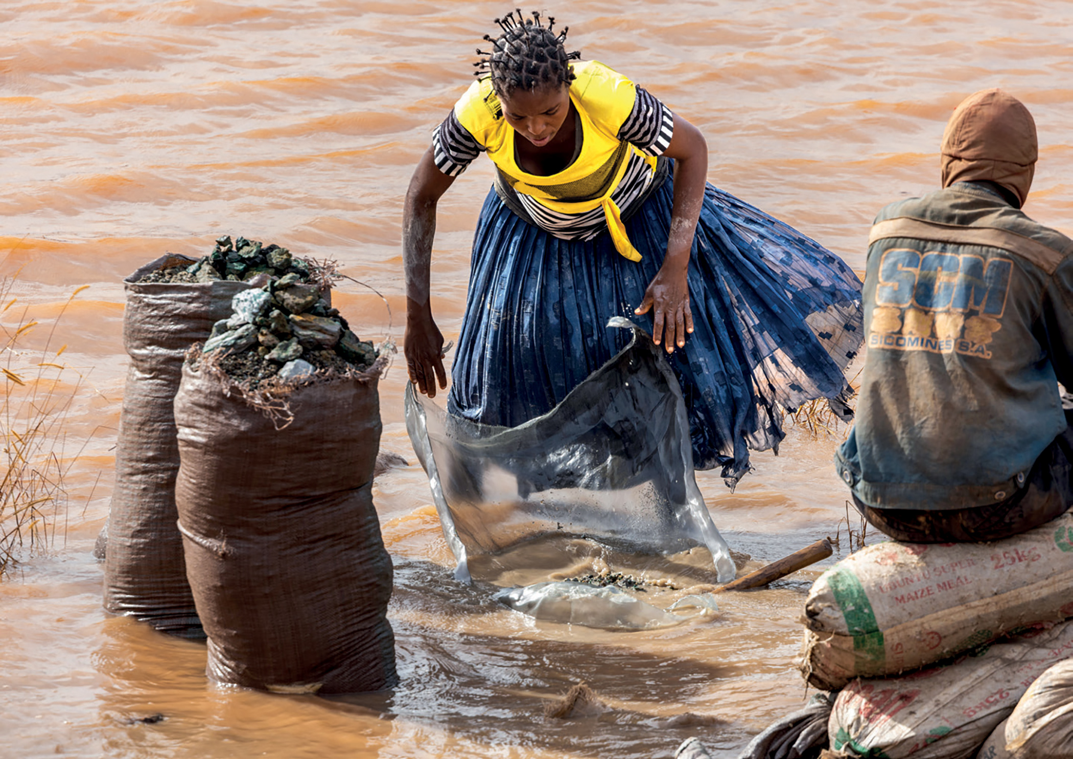 A woman washes cobalt and copper. Water polluted by mining activities is reported to cause vomiting, urinary infections and increased rates of miscarriage.