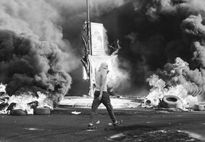 A young man walks through fire and smoke near the city of Jenin’s main hospital during clashes with the Israeli military in July 2023. Photo: Víctor Cabo