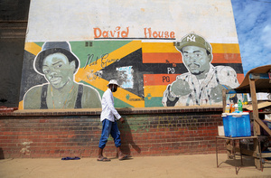 A man walks past a mural of popular ZimDancehall artists, Kinnah (left) and Killer T (right), in Zimbabwe's most populous slum Mbare. The young musicians have become heroes in this township, the birthplace of the subversive genre.Photo: Mark Mhukayesango