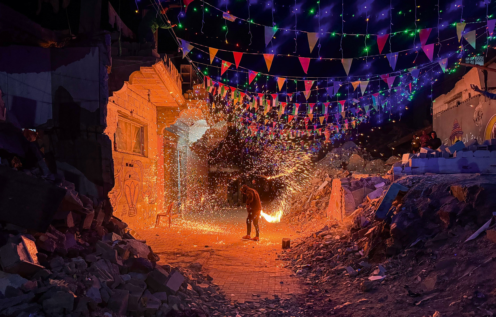 Palestinian youths in Gaza set off fireworks to celebrate Ramadan on 16 March 2024 amid the rubble of buildings destroyed by Israeli forces.