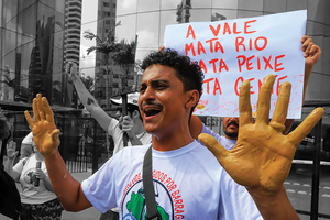 An activist in Belem, Brazil, bares his muddy palms in protest of COP 30’s major sponsor Vale — on the 10th anniversary of the deadly Mariana dam disaster linked to the mining company. The sign reads: "Vale kills rivers, kills fish, kills people.".Photo: AP Photo/Paulo Santos/Alamy