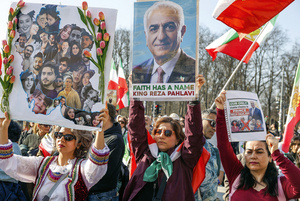 Members of the Iranian diaspora hold posters of Reza Pahlavi while waving the pre-revolution flag at an anti-regime protest in Berlin on 6 March 2026. Many in the emigrant community remain nostalgic for the deposed monarchy, while others are deeply critical of it.Photo: Imagebroker via Alamy