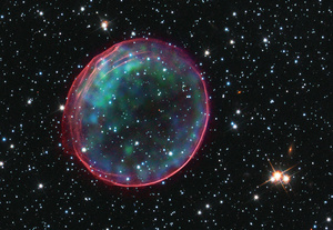 The remnants of a supernova, located in the Large Magellanic Cloud – a satellite galaxy to our Milky Way, 160,000 light years distant. The image combines optical data from the Hubble Space Telescope showing the expanding blast wave in pink, and data from the Chandra space observatory showing x-rays from heated material in green and blue.Photo: NASA/Chandra X-Ray Observatory