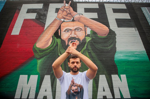Arab Barghouti poses in front a mural of his father, Marwan Barghouti, on 19 September 2025. The mural was painted in Belfast by artist Marty Lyons, and commissioned by Mothers Against Genocide.Photo: Liam Mcburney/PA Images